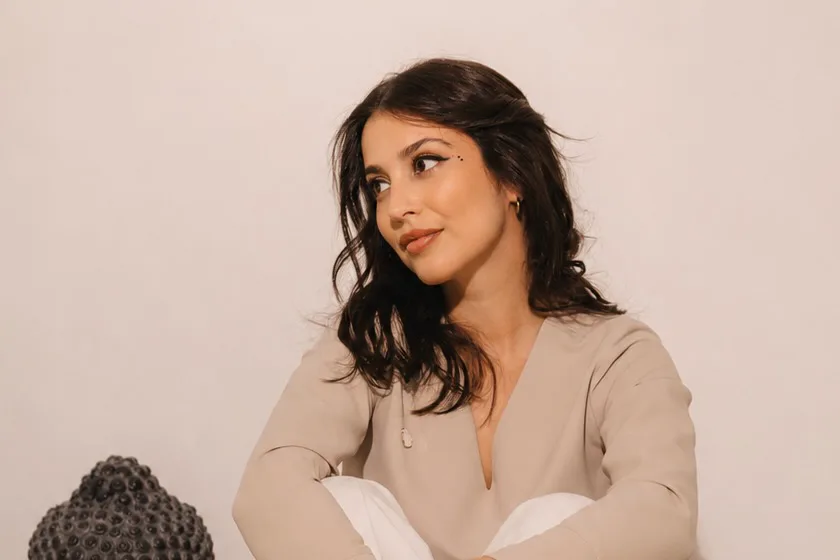 Ana Moreira Leal sentada no chão, descontraída, ao lado de uma escultura de Buda